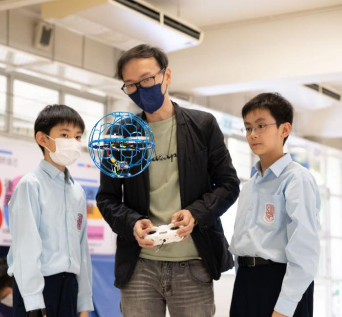 An instructor and students working with a spherical drone ball