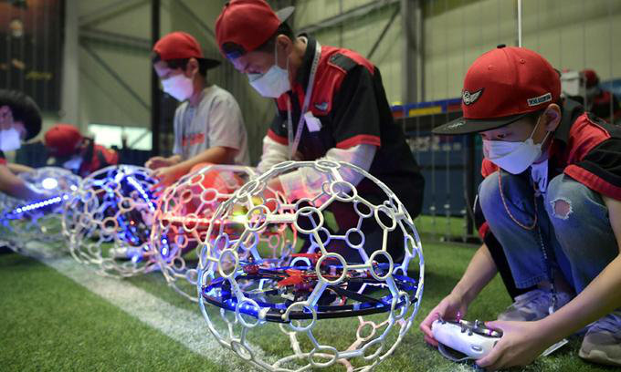 Pilots preparing illuminated drone balls beside the arena