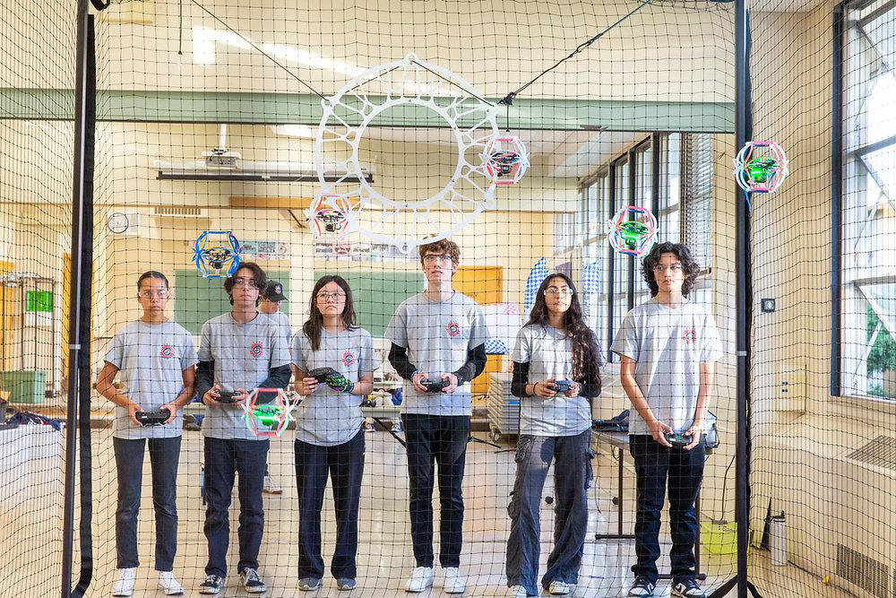 A group holding drone controllers beside a drone soccer goal
